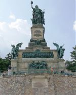 Das Niederwalddenkmal mit der "Germania" liegt oberhalb der Stadt Rüdesheim am Rhein. Zu seinen Füßen befinden sich die Weinlagen des Rüdesheimer Berges.  Das Denkmal soll an die Einigung Deutschlands 1871 erinnern